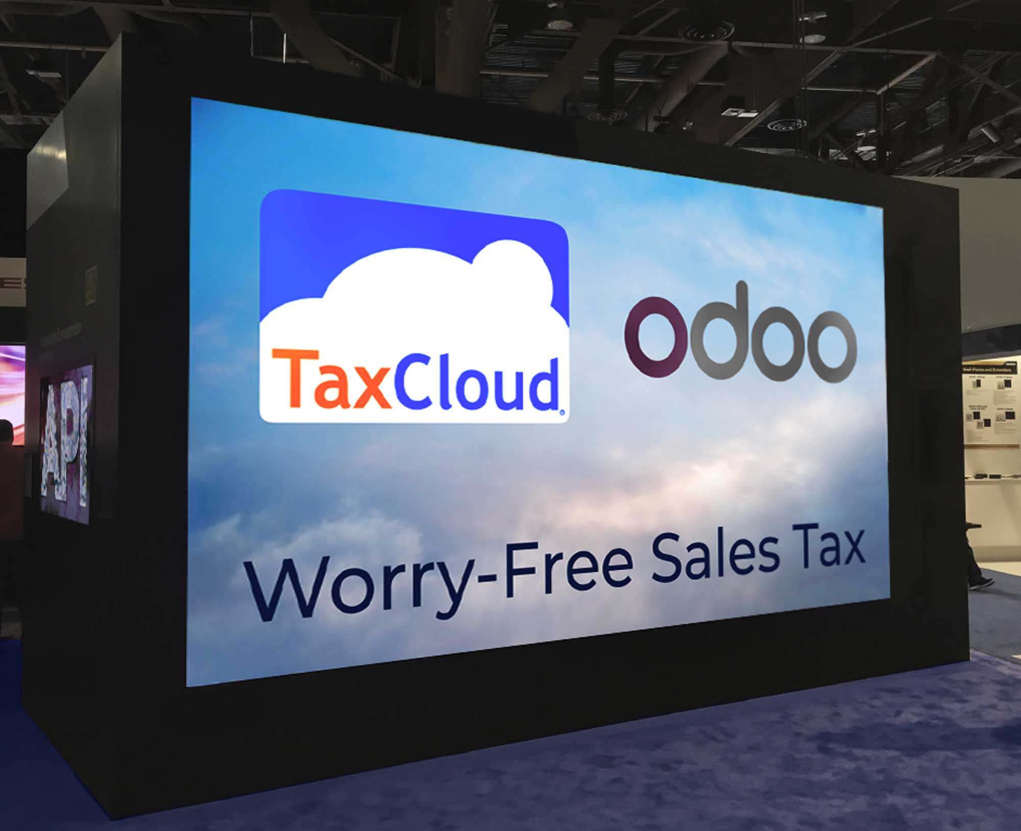 View of a trade show booth with a large TaxCloud and Odoo video playing made by UX/UI Designer Priscilla Prentice