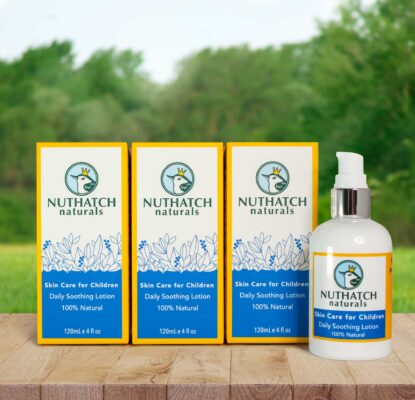 3 nuthatch natural skin cream bottles on a wood table in front of a sunny grassy field